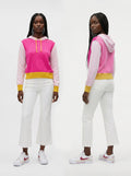 A model is shown from the front and back wearing a color-blocked hoodie with a bright pink and light pink body, a yellow waistband, and white pants with white sneakers.