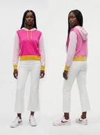 A model is shown from the front and back wearing a color-blocked hoodie with a bright pink and light pink body, a yellow waistband, and white pants with white sneakers.
