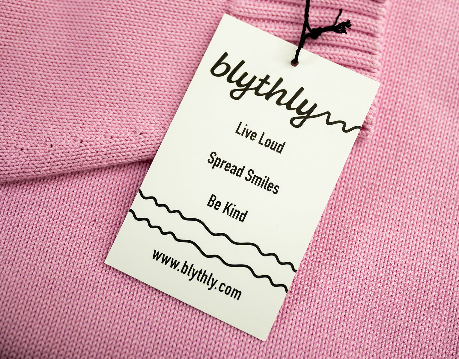 Blythly tag on a pink fabric background